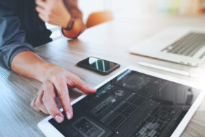 Man using tablet on desk with phone and laptop