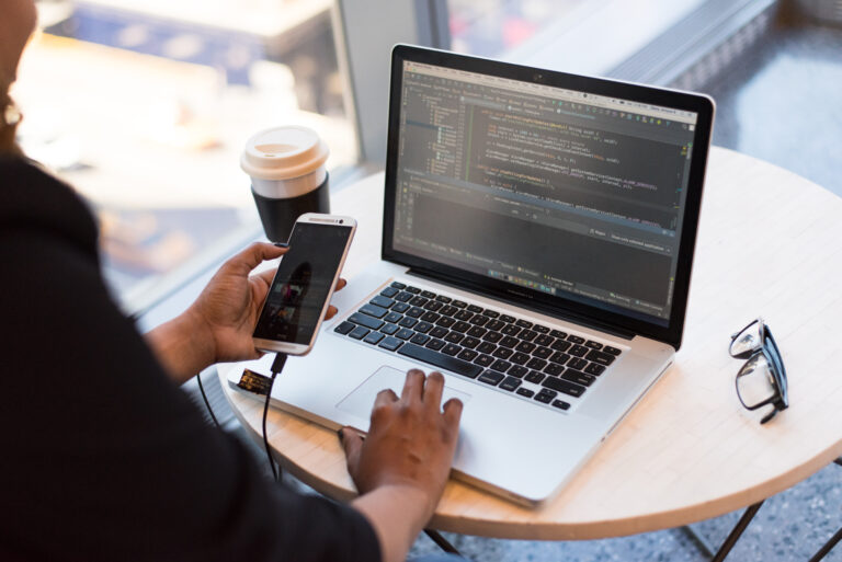 Person using laptop and phone simultaneously